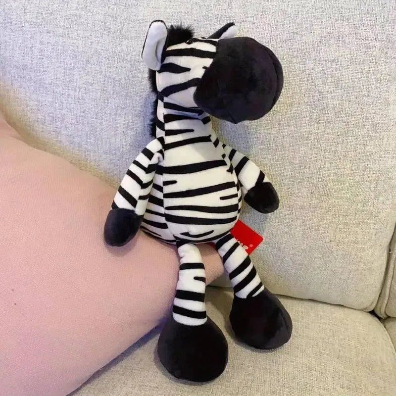 Doudou zèbre en peluche noir et blanc posé sur un canapé clair pour bébé