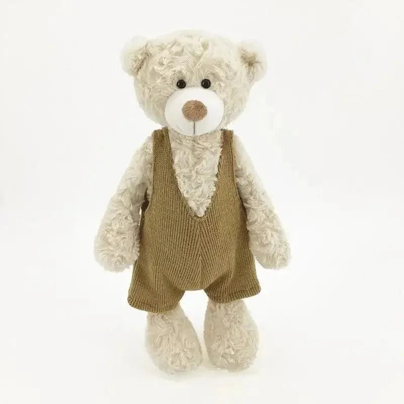 Ours en peluche beige avec salopette marron sur fond blanc, doudou pour bébé.