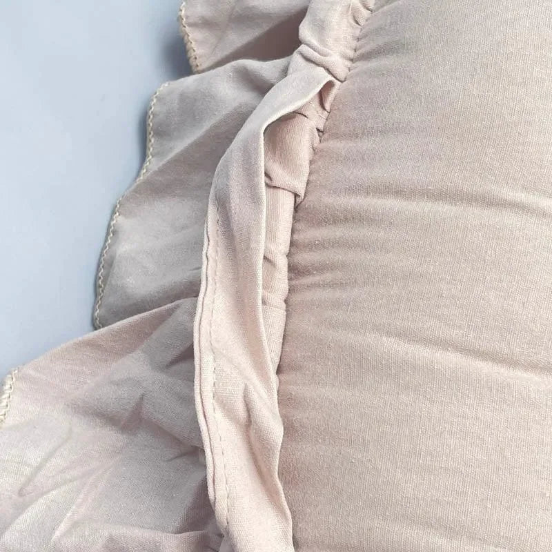 Gros plan sur un réducteur de lit bébé avec tissu beige et bords froncés doux.