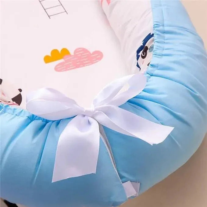 Réducteur de lit bébé bleu décor panda, coussin doux avec ruban blanc noué.