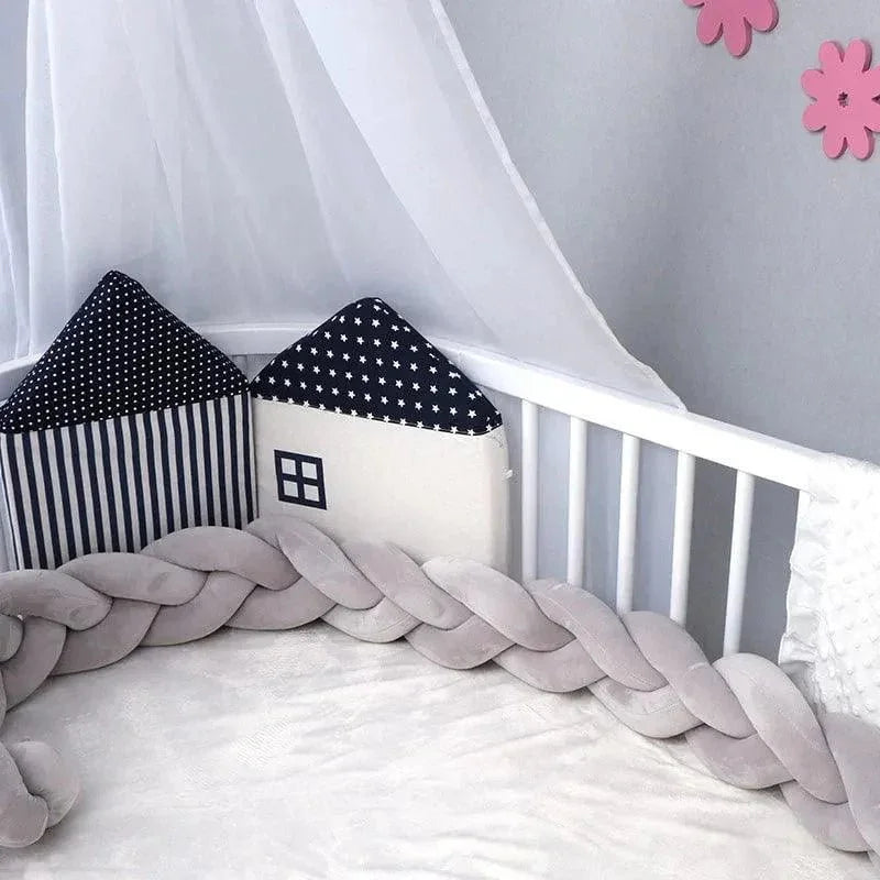 Tour de lit tressé gris dans un lit bébé, coussins maison, décoration douce