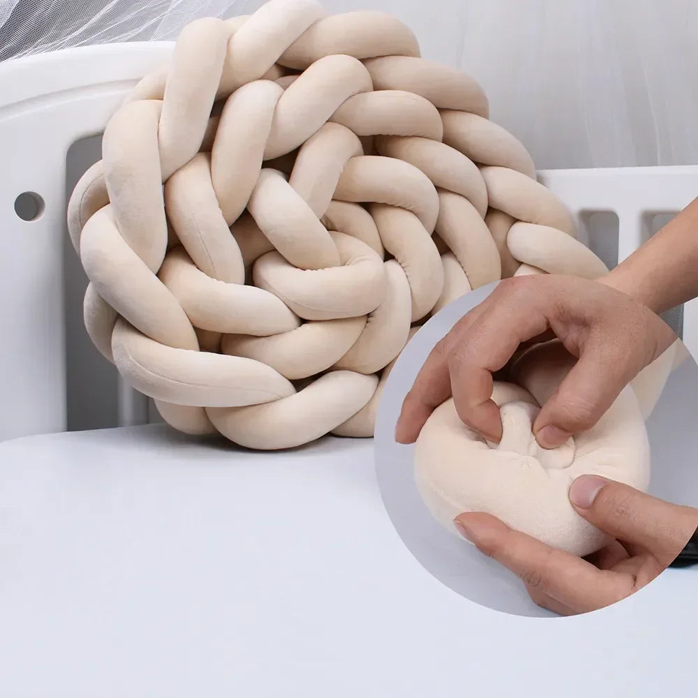 Tresse de lit bébé beige moelleuse posée dans un lit blanc avec détail tissu doux.