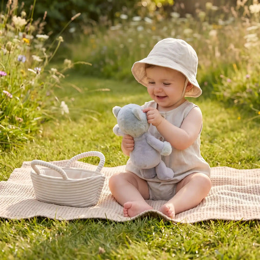 bébé-joue-avec-son-doudou-chat-sur-herbe