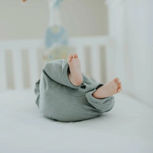 Pieds de bébé en pyjama allongé dans un lit blanc, ambiance douce et sécurisée