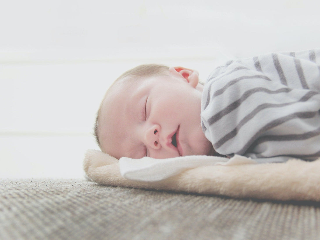 Bébé endormi sur une couverture douce, pyjama rayé, atmosphère rassurante et paisible