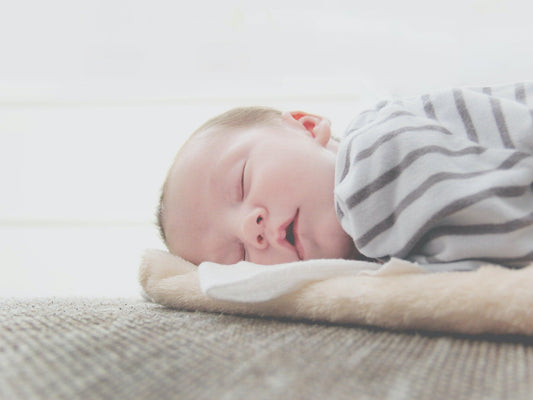 Bébé endormi sur une couverture douce, pyjama rayé, atmosphère rassurante et paisible