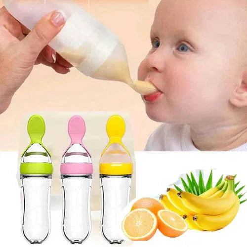 Bébé mangeant une panade avec cuillère-biberon, fruits frais et biberons colorés au premier plan