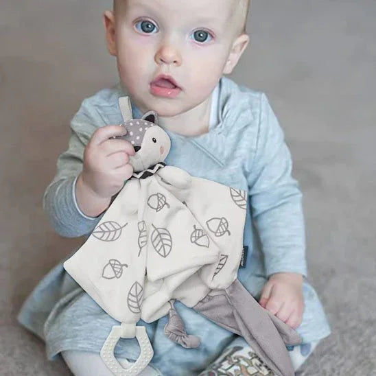 Bébé assis tenant un doudou doux motif feuilles, accessoire apaisant pour bébé