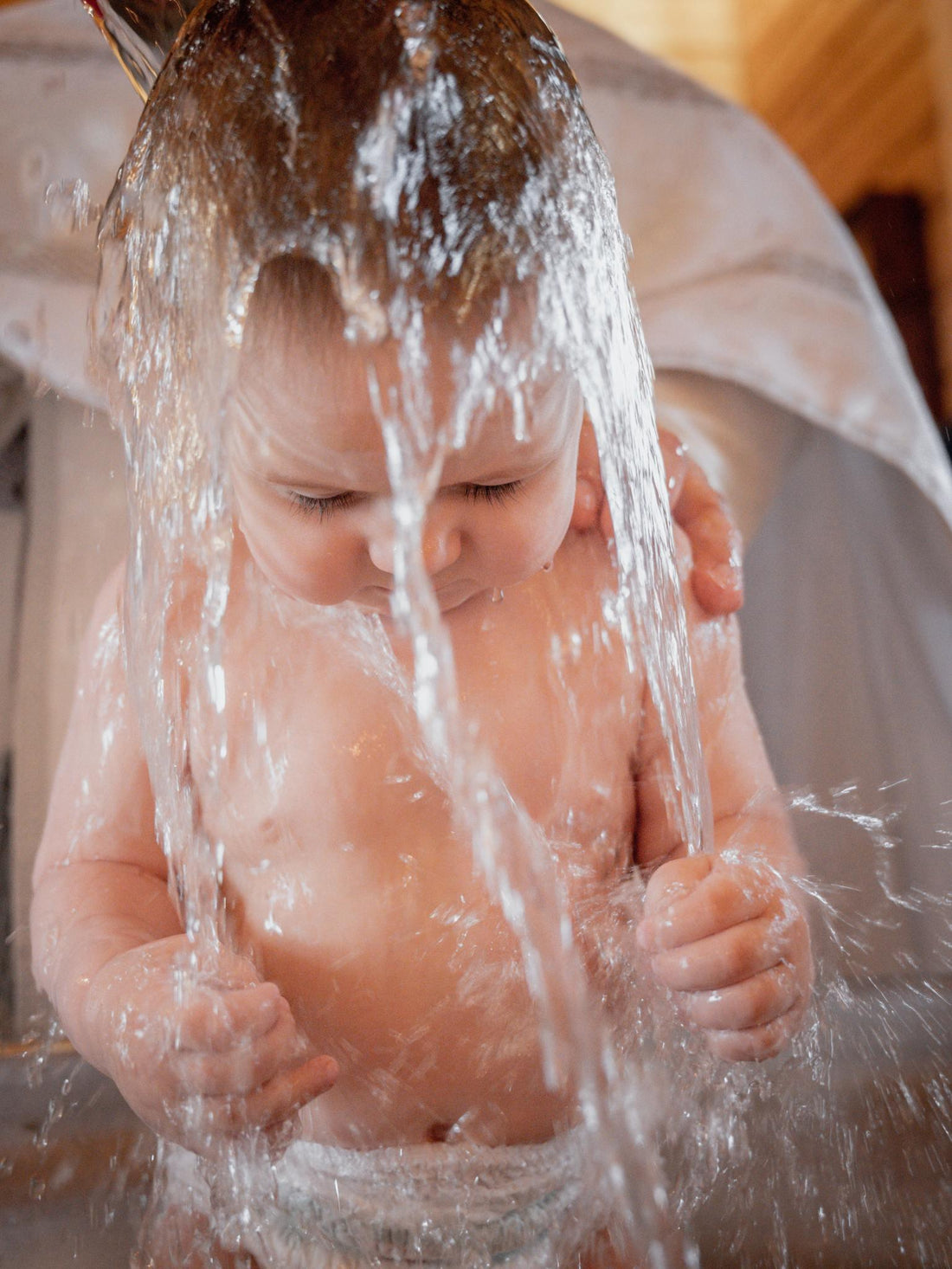 Bébé assis, eau versée sur la tête, protection bain enfant, moment toilette sécurisé