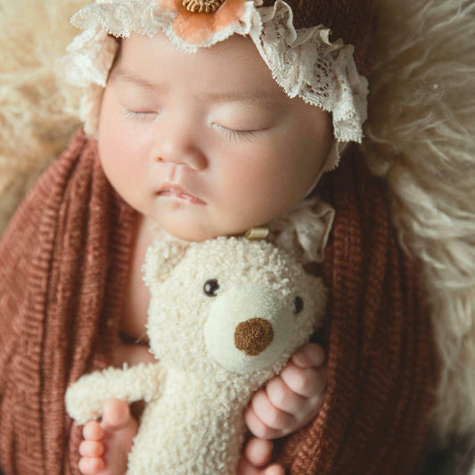 Bébé endormi tenant un doudou peluche, vêtement marron, ambiance douce et rassurante