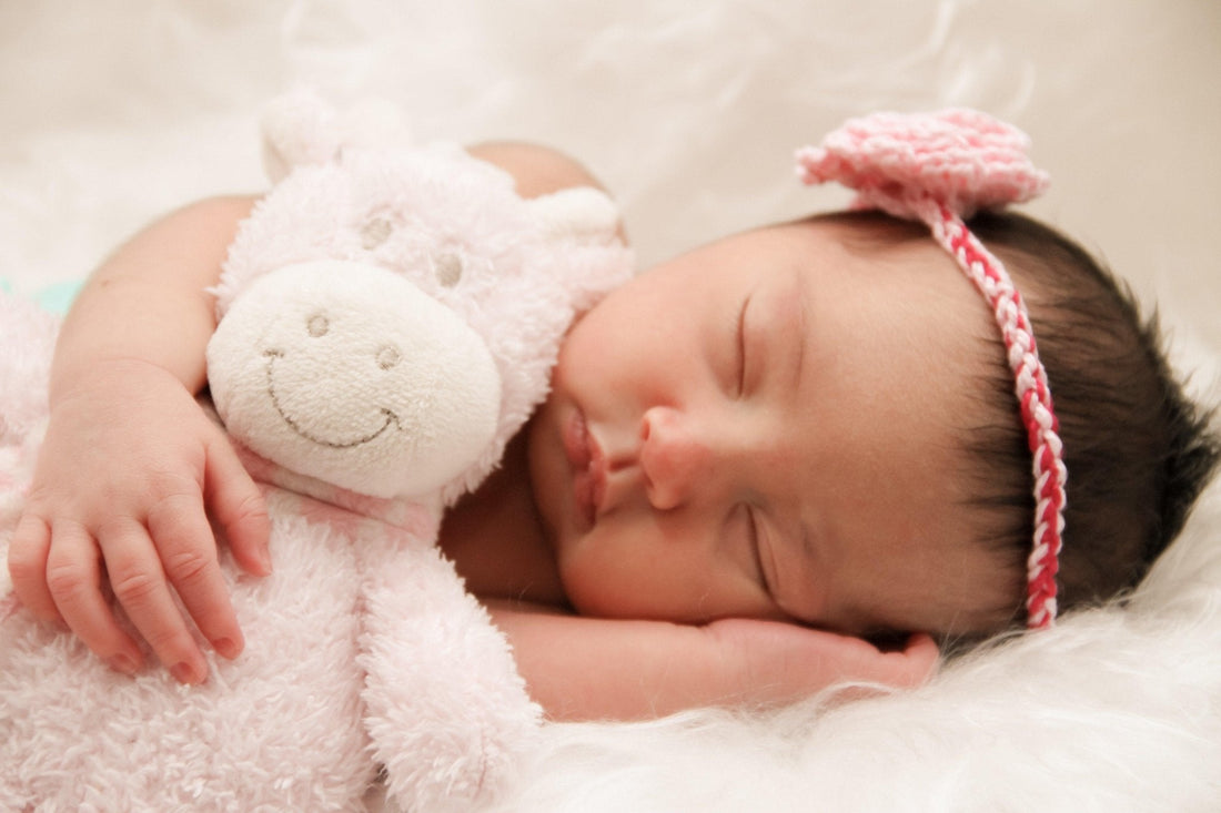 Bébé dormant paisiblement avec doudou peluche sur un fond doux, apaisement sommeil