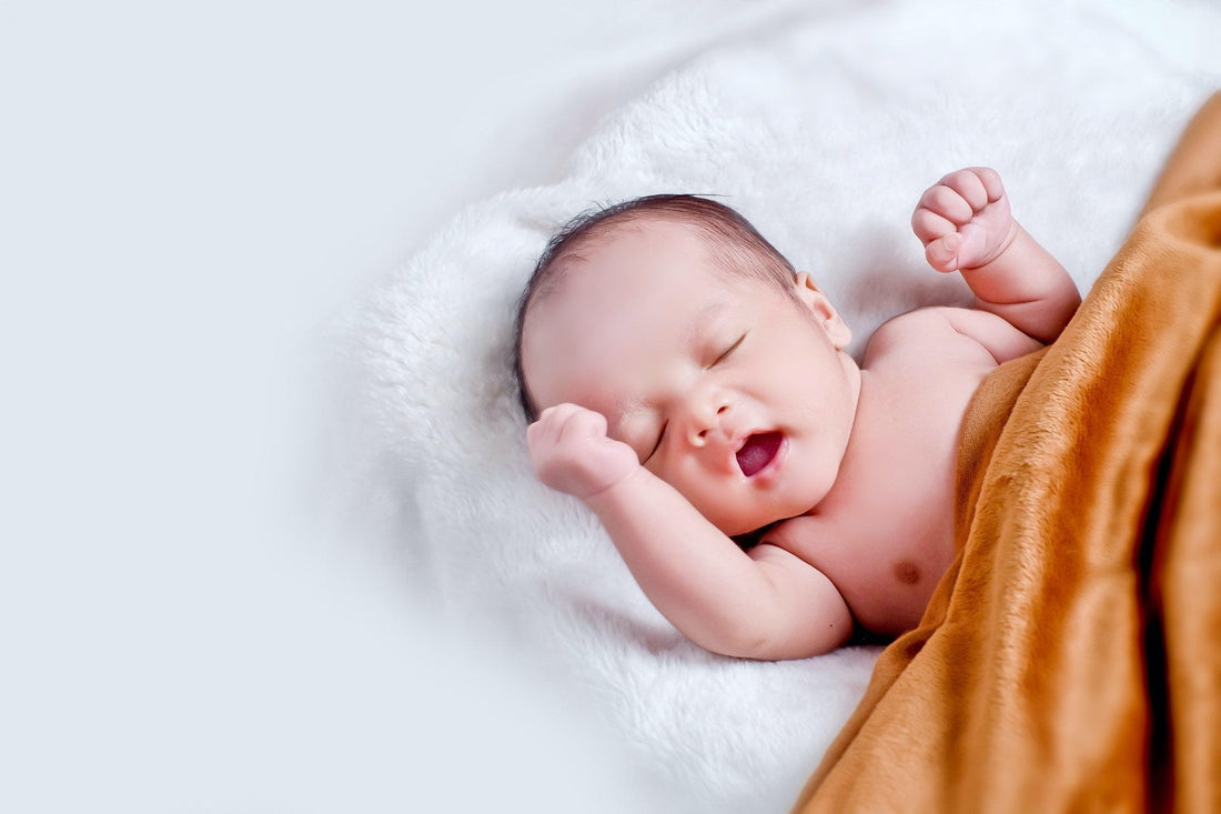 Bébé qui dort paisiblement sur une couverture douce, sourire au visage, sommeil apaisé