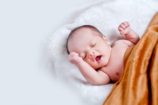 Bébé qui dort paisiblement sur une couverture douce, sourire au visage, sommeil apaisé