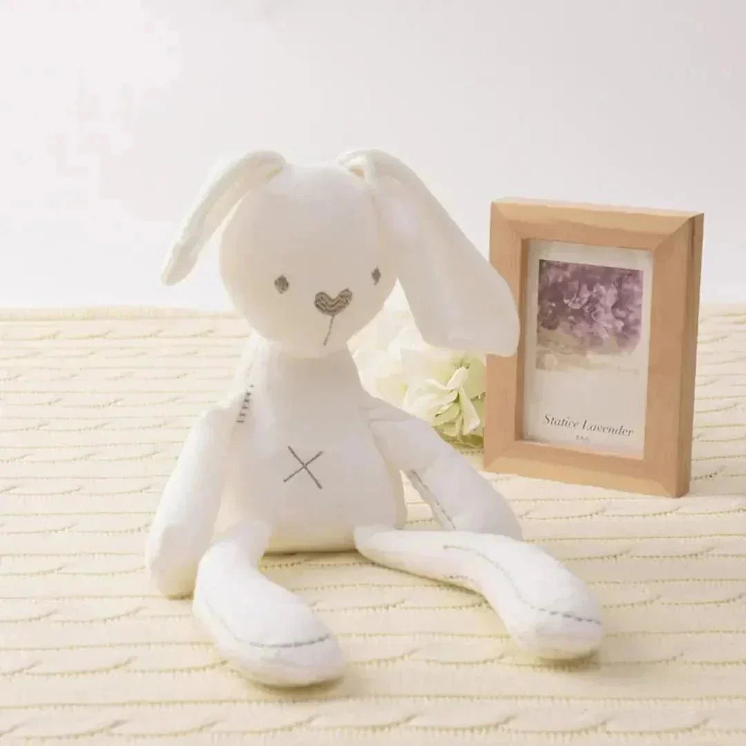 Doudou lapin blanc en peluche posé sur un lit bébé, ambiance douce et rassurante.