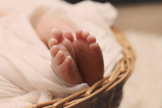 Pieds de bébé reposant sur une couverture douce dans un panier, ambiance cocooning