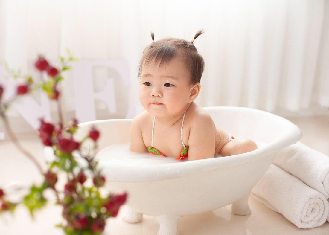 Bébé dans une petite baignoire blanche, lumière naturelle, serviettes roulées, ambiance douce