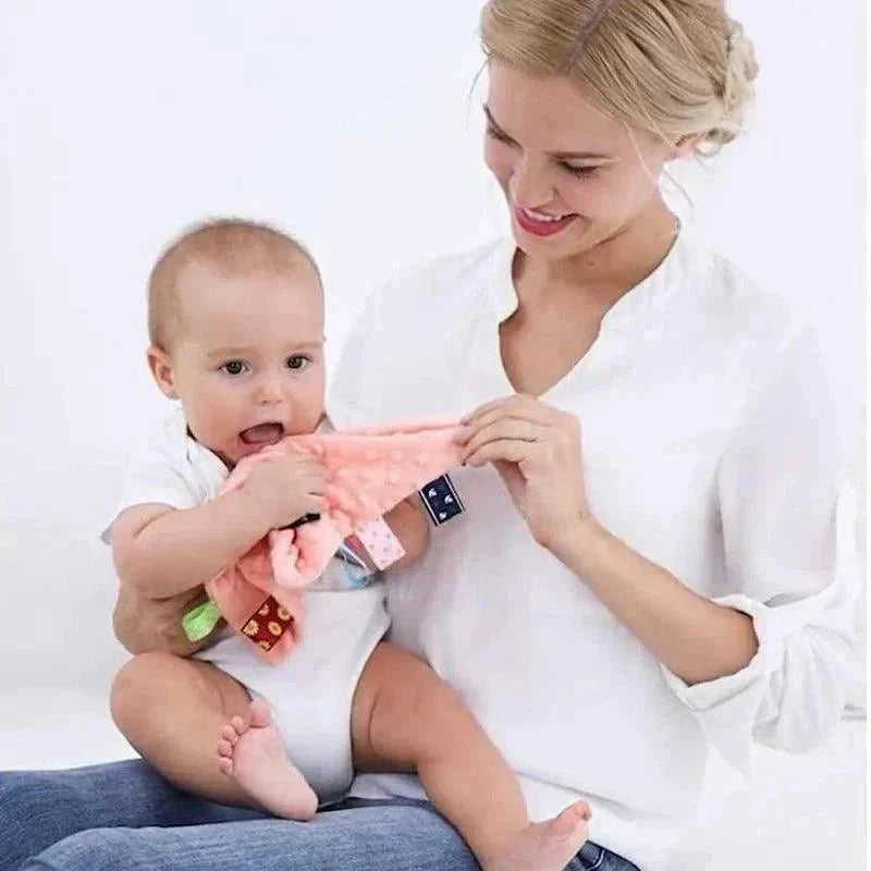 Bébé avec sa maman tenant un doudou sensoriel rose, accessoire rassurant pour sommeil bébé.