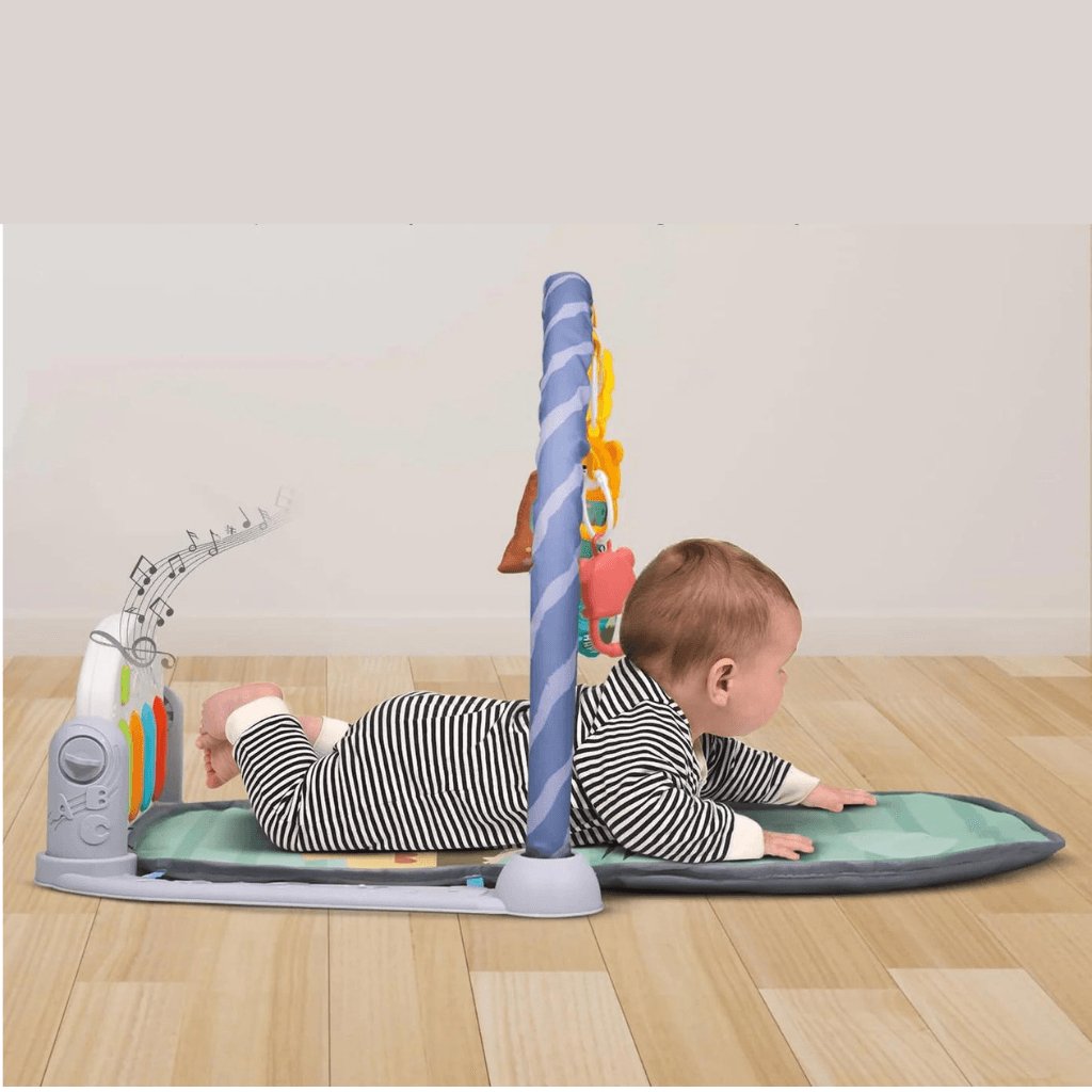 Bébé allongé sur un tapis d’éveil musical avec jouets suspendus, sol en bois clair.
