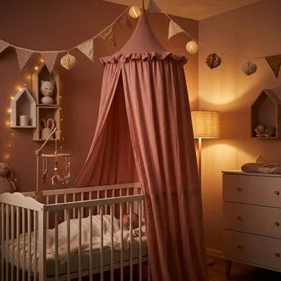 Ciel de lit rose dans une chambre bébé avec veilleuse allumée