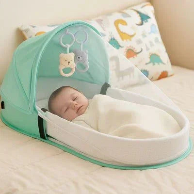 Lit bebe de voyage turquoise posé sur le lit