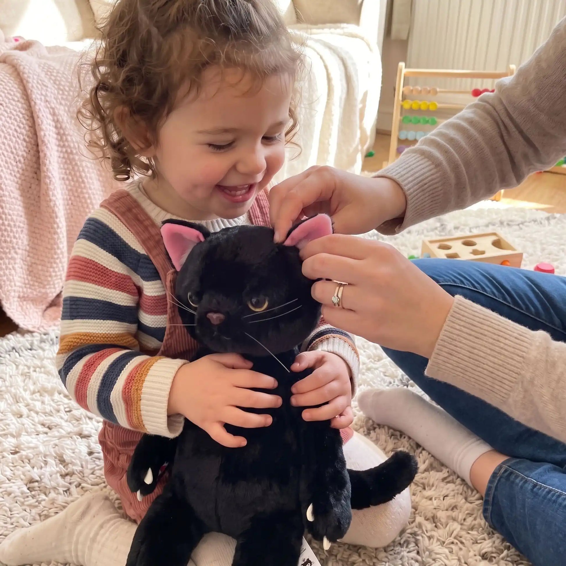 maman et bebe fille joue avec peluche chat noir