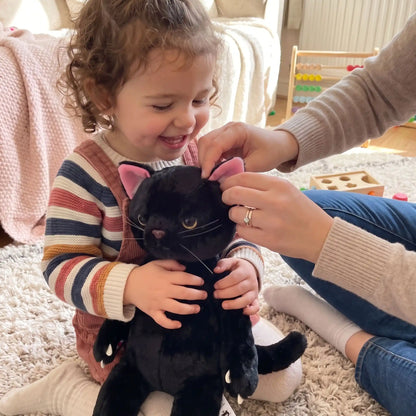 maman et bebe fille joue avec peluche chat noir