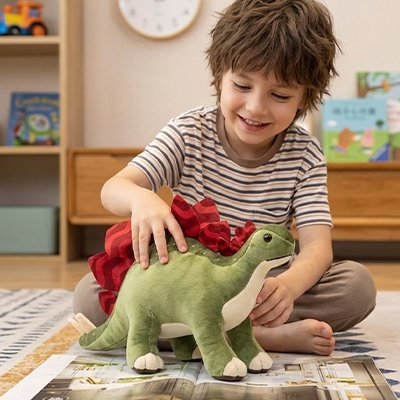 Peluche dinosaure avec un garcon assis par terre 
