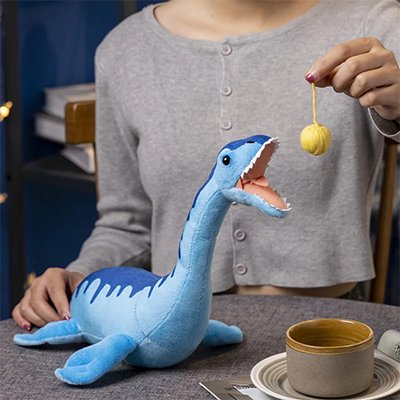 Peluche dinosaure qui mange une boule jaune
