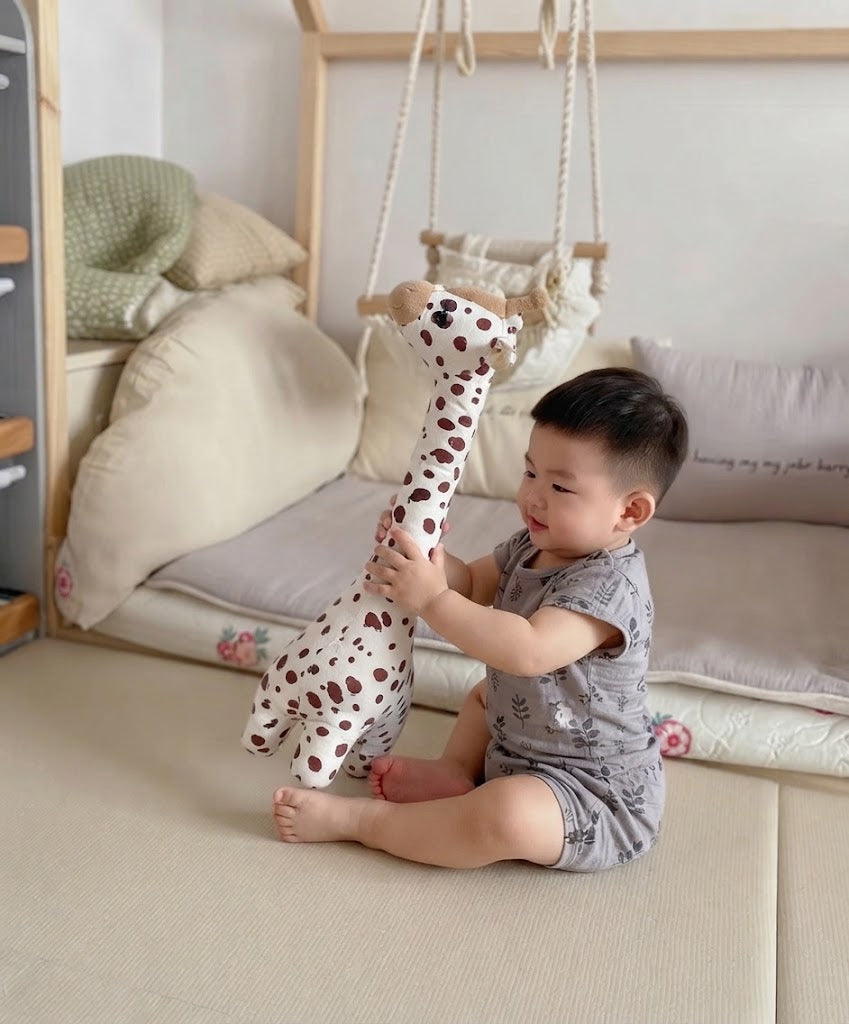 petit garcon qui caline sa peluche girafe