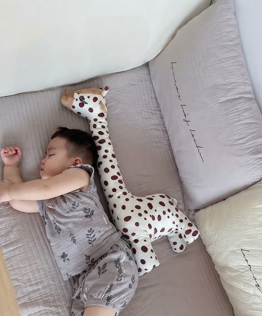 petit garcon qui dort avec sa peluche girafe geante 
