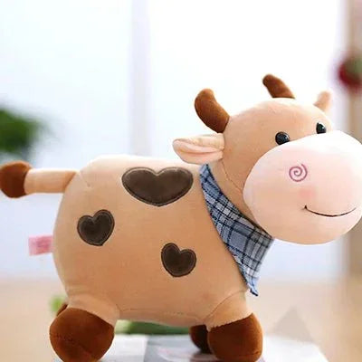 Peluche vache avec foulard bleu posé sur meublle