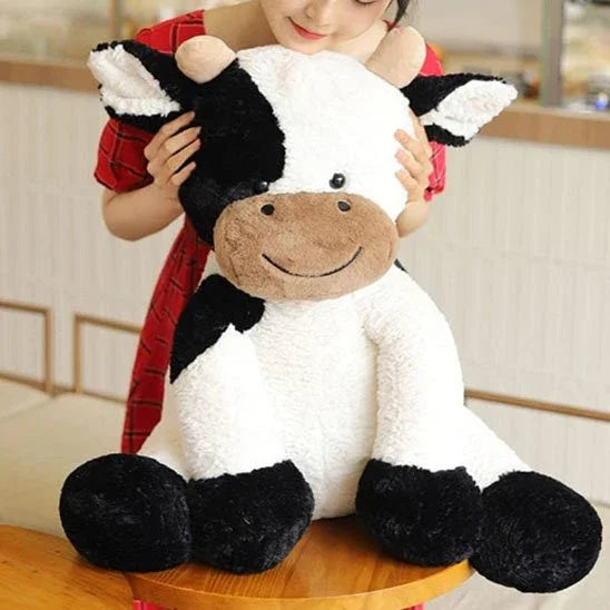 Peluche vache de 50 cm avec une jeune fille qui tient les oreilles