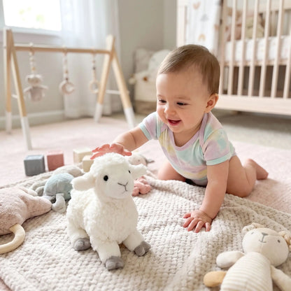 Bébé souriant joue avec un doudou mouton doux, idéal pour l'éveil et le confort - Nanoukid